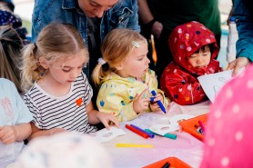 Three children colouring in paper masks