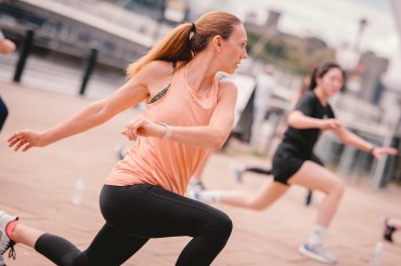 Woman in an orange tank top and black leggings taking part in exercises