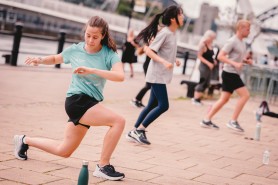 Woman in a blue t-shirt and black shorts bending into a lunge