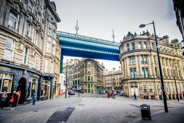 A scene of Newcastle upon Tyne’s Quayside area with ornate buildings and the Tyne Bridge overhead
