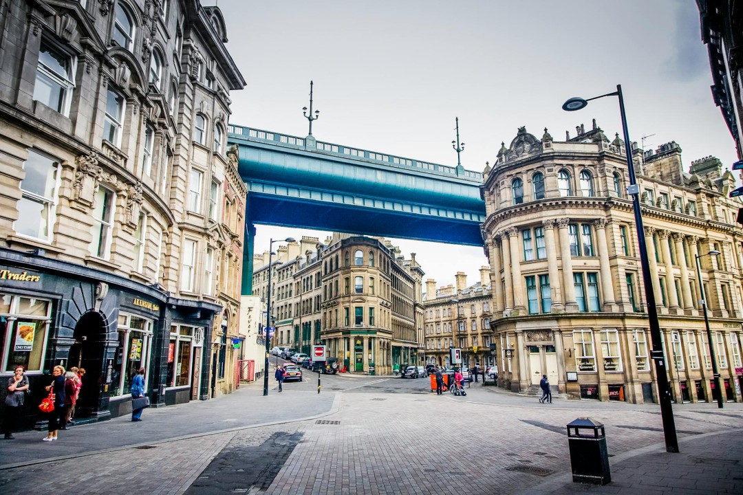 A scene of Newcastle upon Tyne’s Quayside area with ornate buildings and the Tyne Bridge overhead