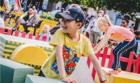Two children playing on colourful foam blocks in an outdoor green space